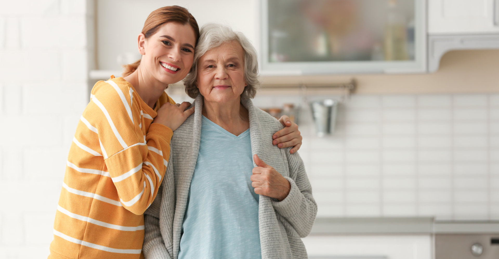 elder woman and her caregiver smiling at the camera