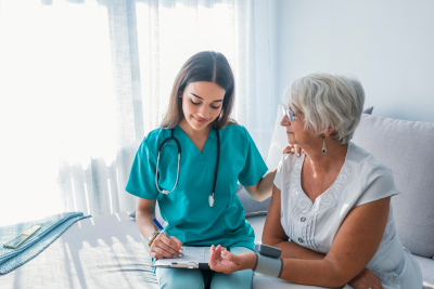 Nurse measuring blood pressure of senior woman at home.